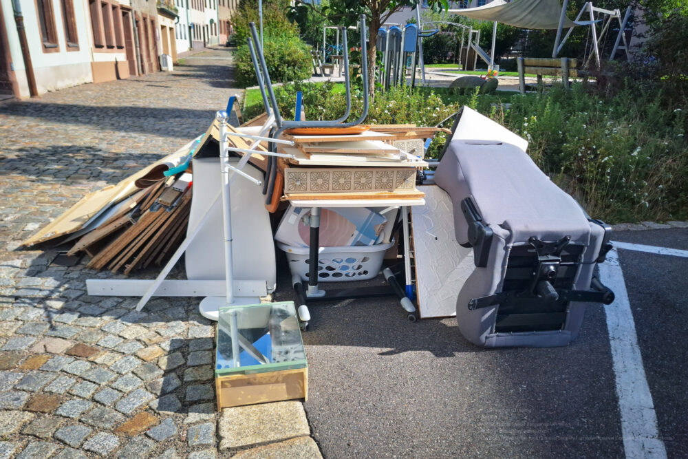A Heap Of Assorted Discarded Household Items And Furniture Piled Up On A Cobblestone Street, Depicting A Bulk Waste Collection Day In An Urban Environment.